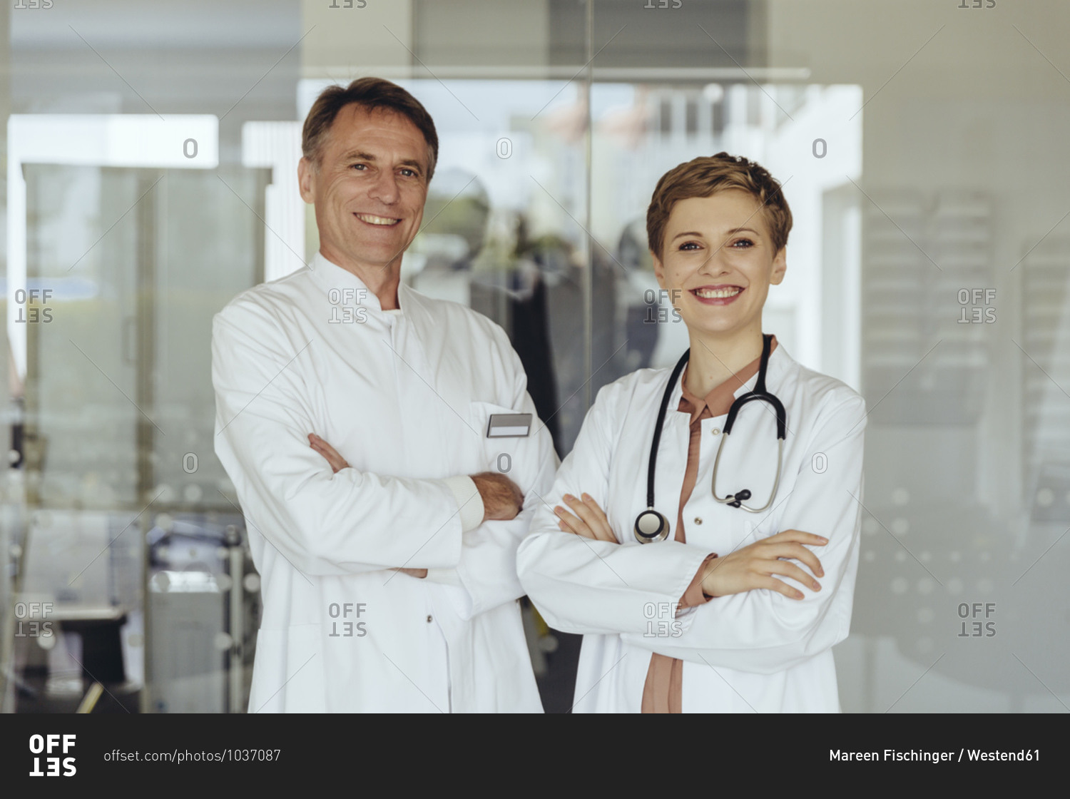 Two confident doctors standing in practice- with arms crossed