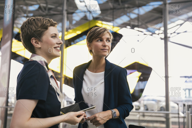Smiling airline employee with tablet and businesswoman at the airport