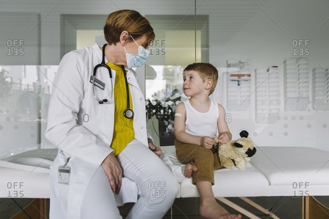 Pediatrician with face mask and toddler in medical practice