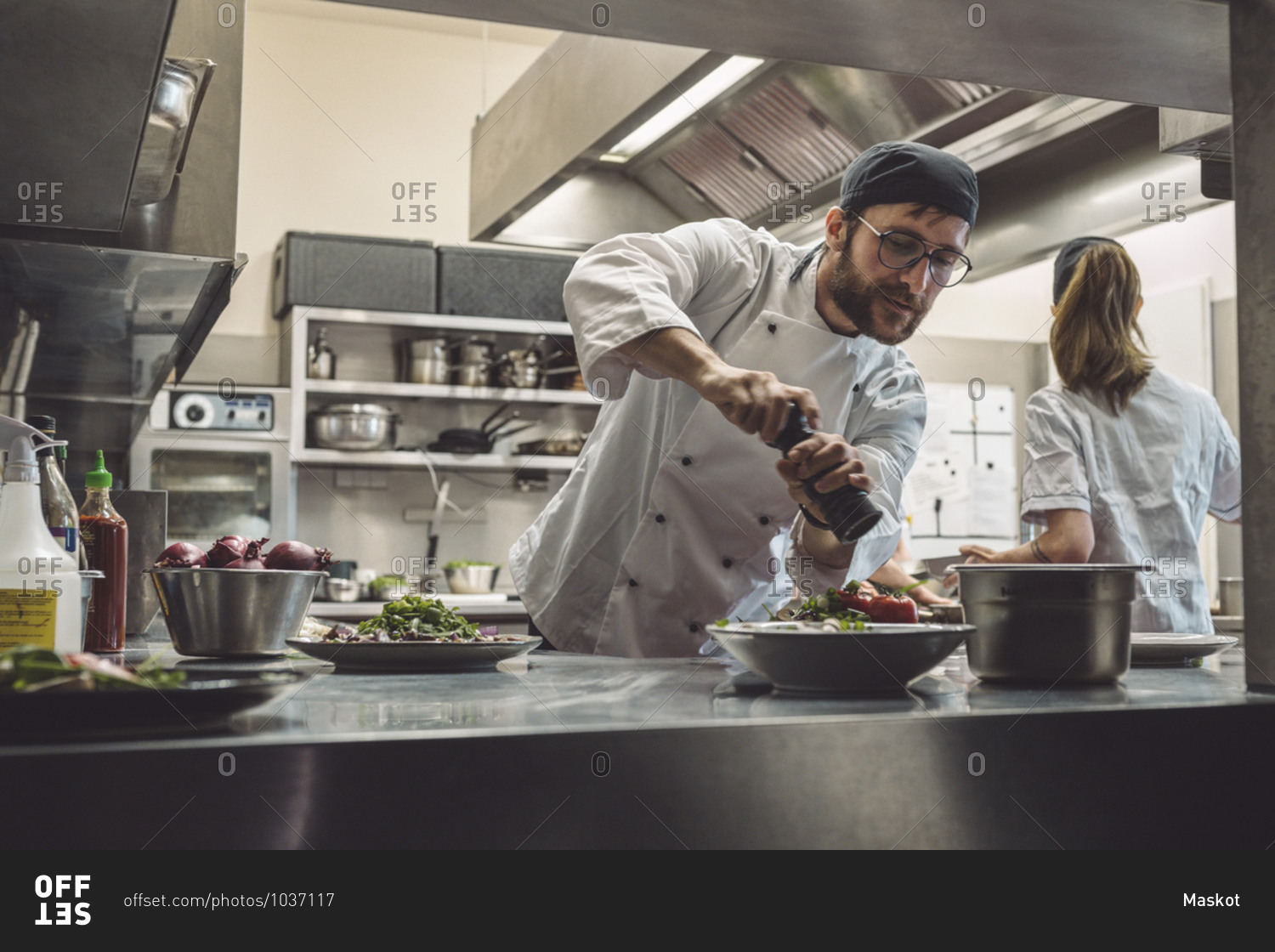 Low angle view of male chef seasoning food in commercial kitchen
