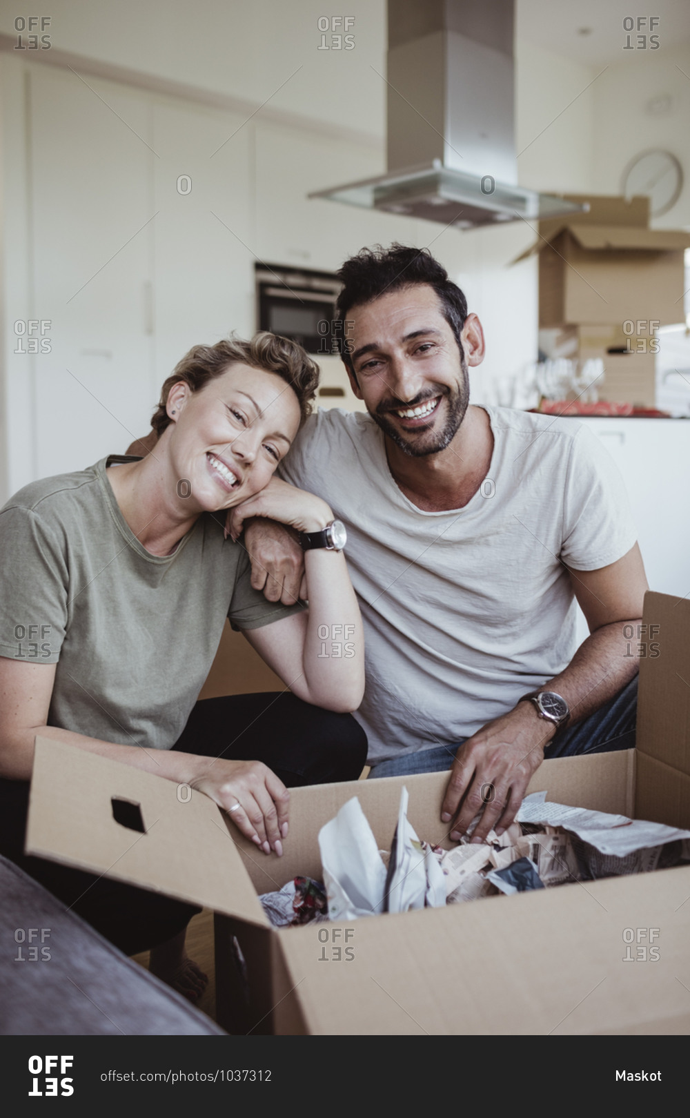 Portrait of smiling male and female partners unpacking cardboard boxes in new house