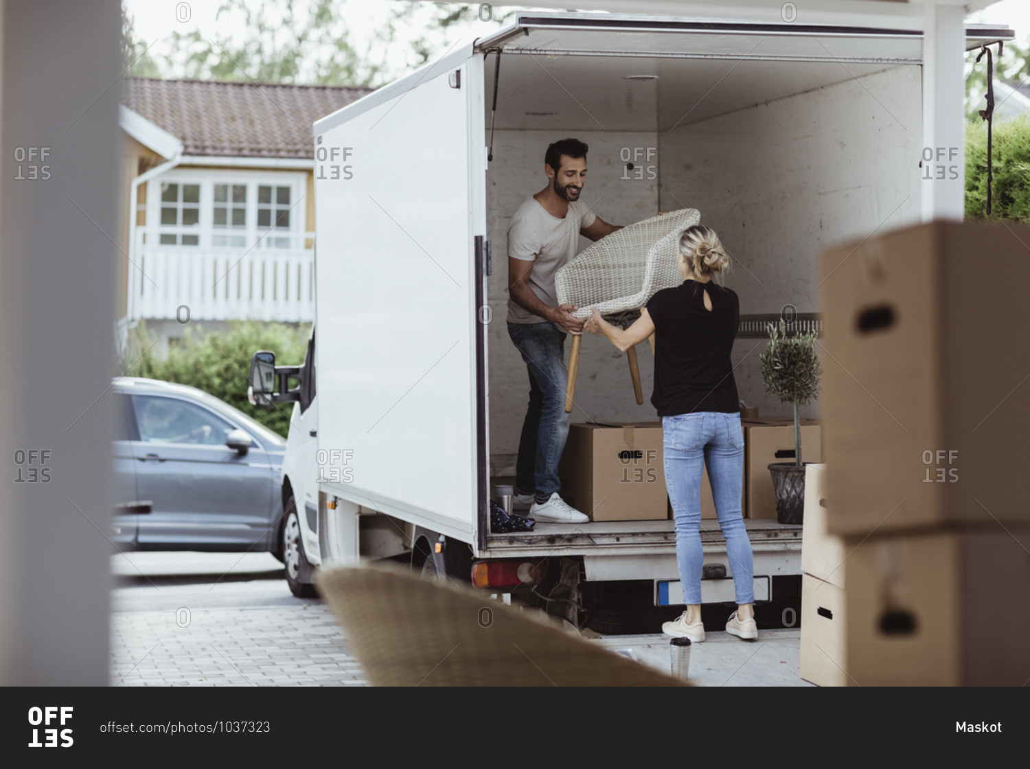 Smiling male and female partners unloading chair from van