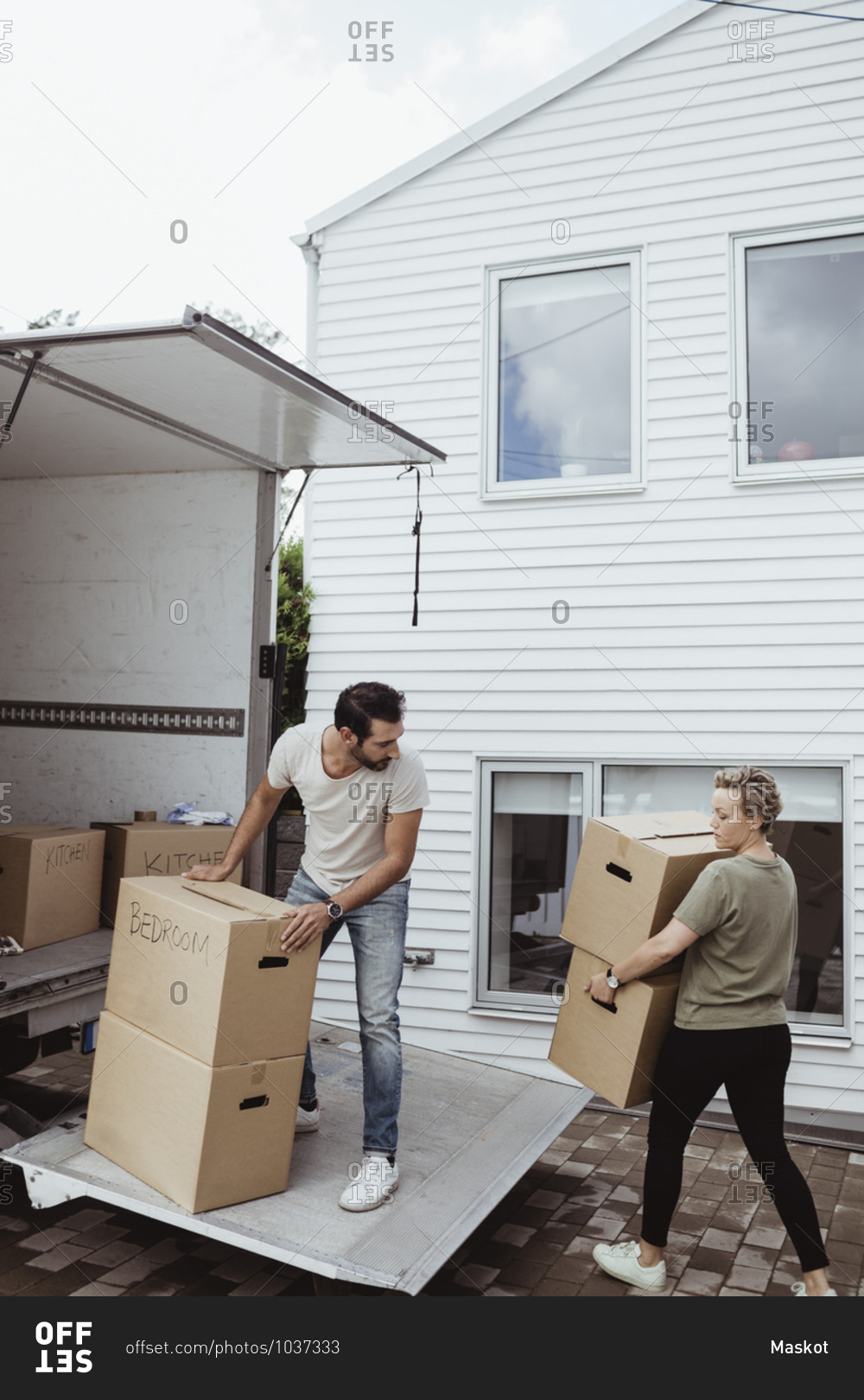 Male and female partners unloading cardboard boxes during relocation