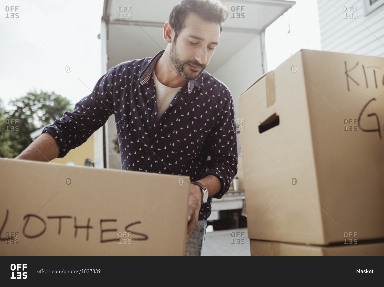 Man unloading cardboard boxes outside van