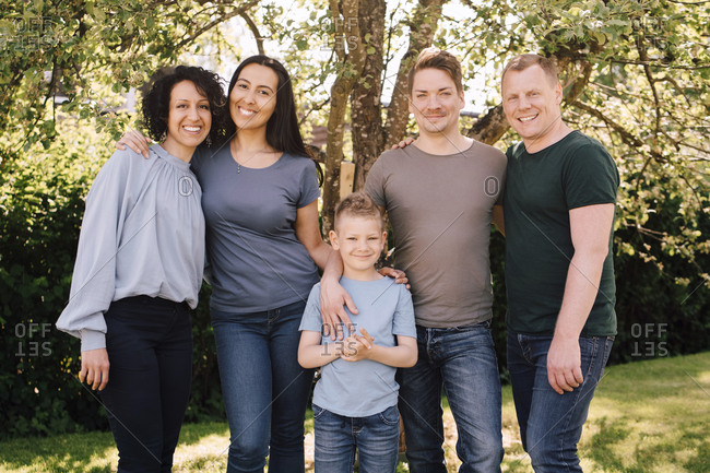 Portrait of smiling homosexual couples with son in backyard