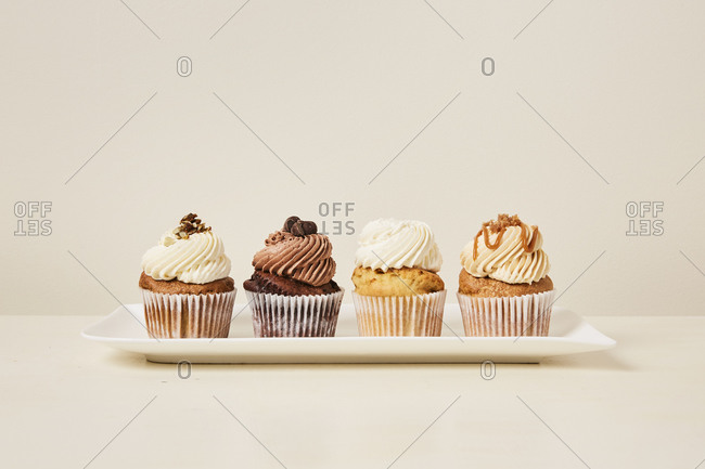 White tray of yummy variety of cupcakes flavors on a cream background