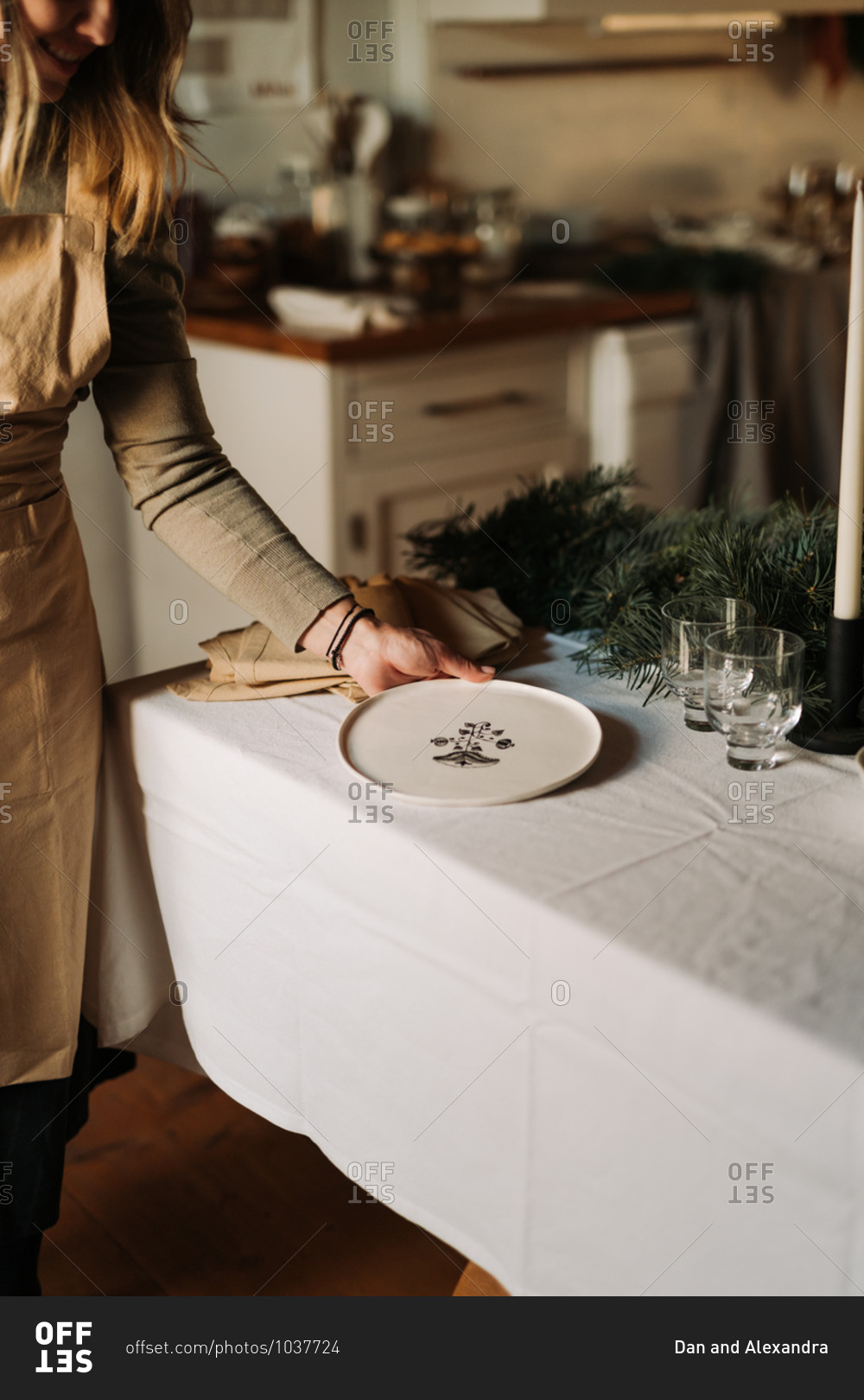 Young woman placing dishes on a table being set for a holiday party