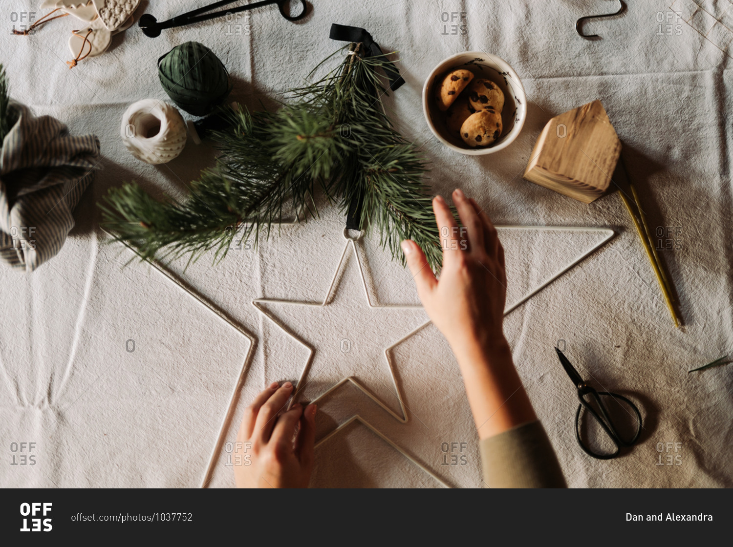 Overhead view of a crafter making Christmas decorations on table with linen tablecloth