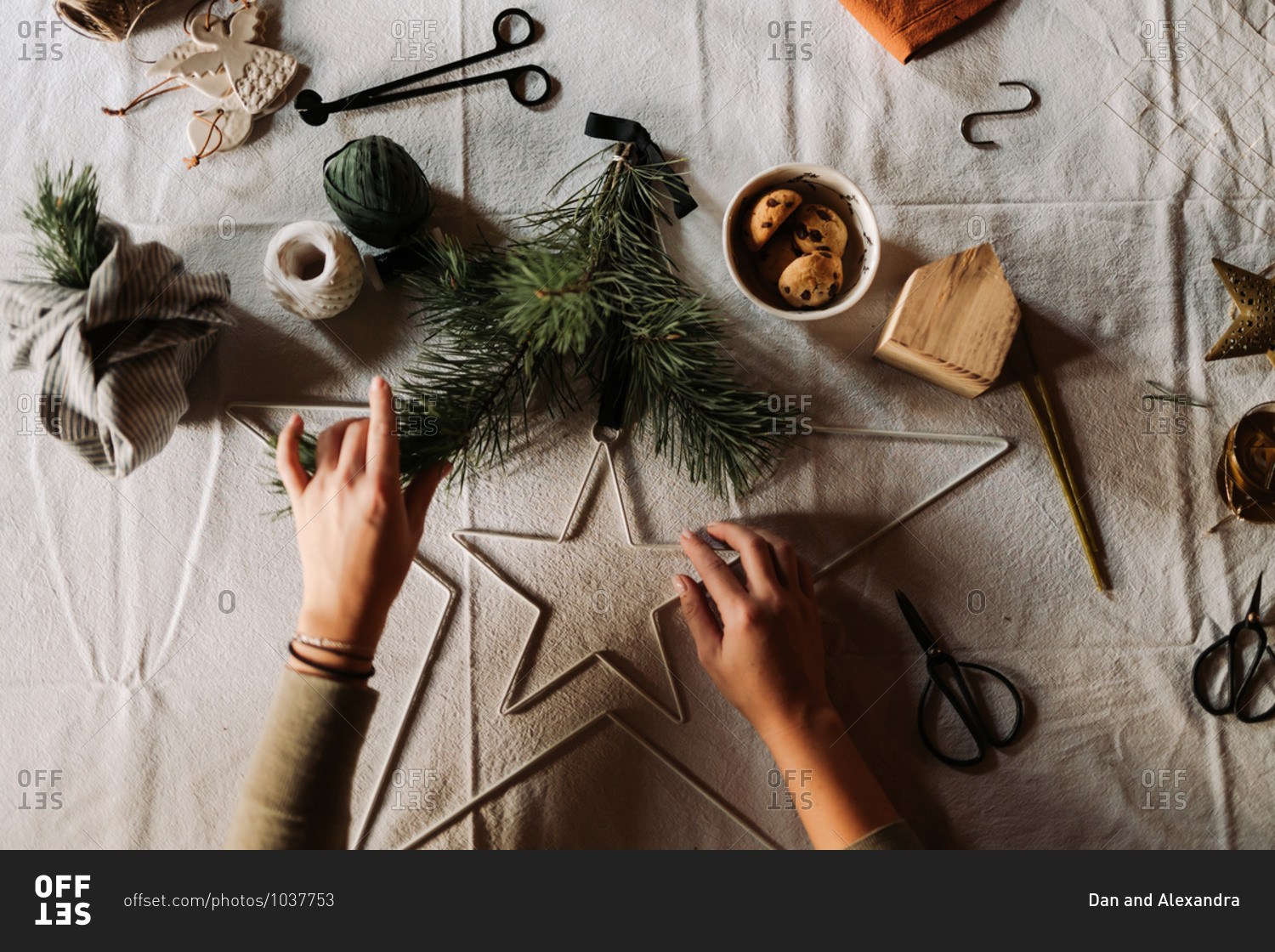 Crafter making Christmas decorations on table with linen tablecloth viewed from above