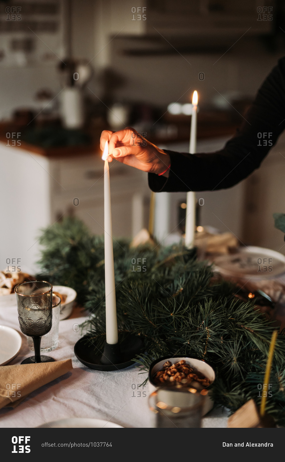 Woman lighting a candlestick on a holiday table set for a dinner party