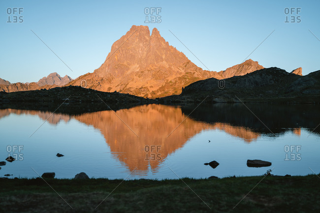 Big mountain reflected on a calm lake during sunset in French Pyrenees