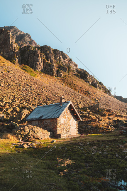 Tiny small hut at the bottom of a rocky hill in Pyrenees