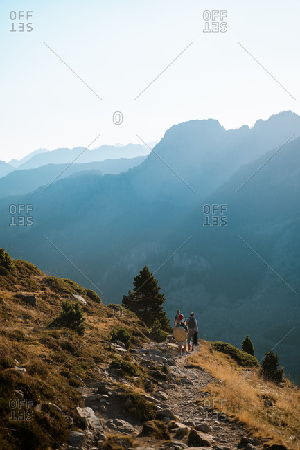 Three male hikers walking down the trail with an amazing view of the mountains in the background