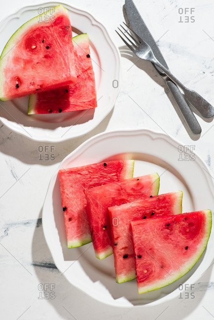 Sliced watermelon served on ceramic white plate over white background