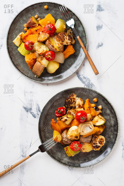 Overhead view of roasted root vegetables cooked with tomatoes, onion and chickpea