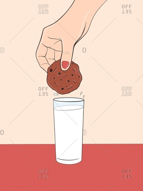 Girl holding homemade cookie above glass of milk