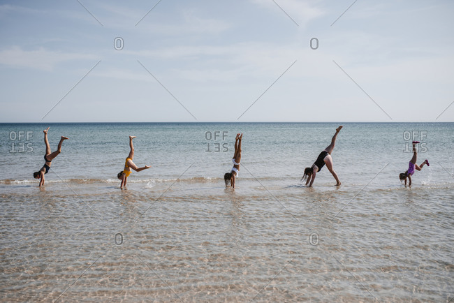 Mother with daughters doing handstand at sea