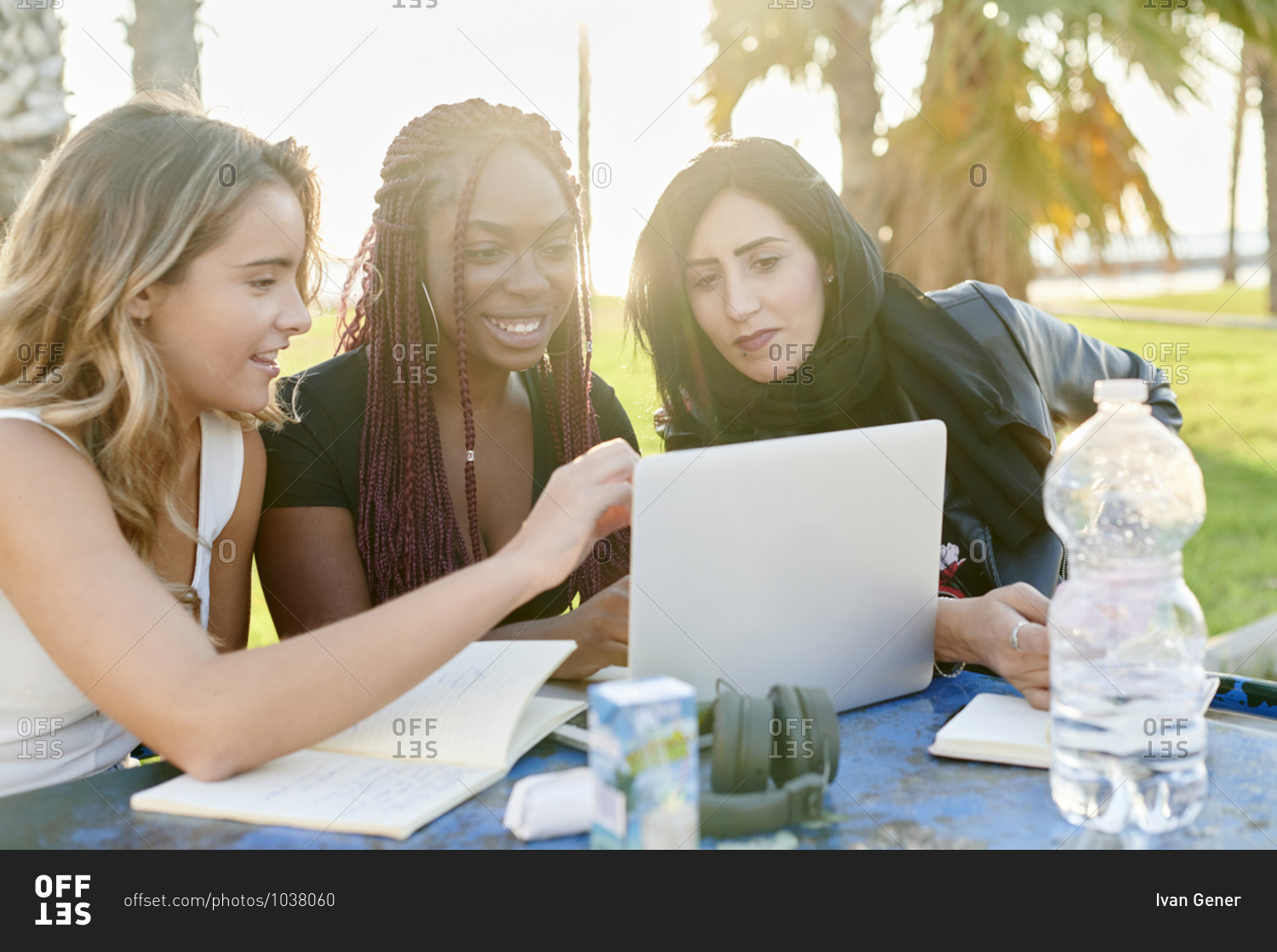 Smiling group of diverse young female university students studying together outside in a park in the afternoon