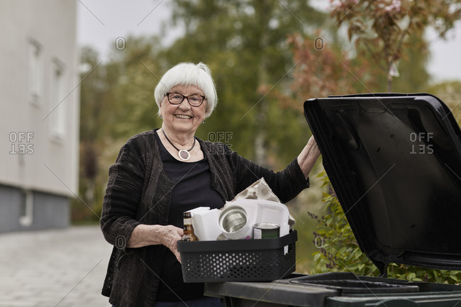 Smiling senior woman carrying recycling rubbish