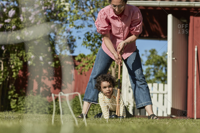 Mother with toddler playing croquet in garden