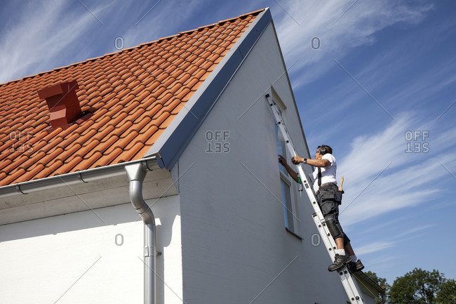 Man on ladder doing house repairs