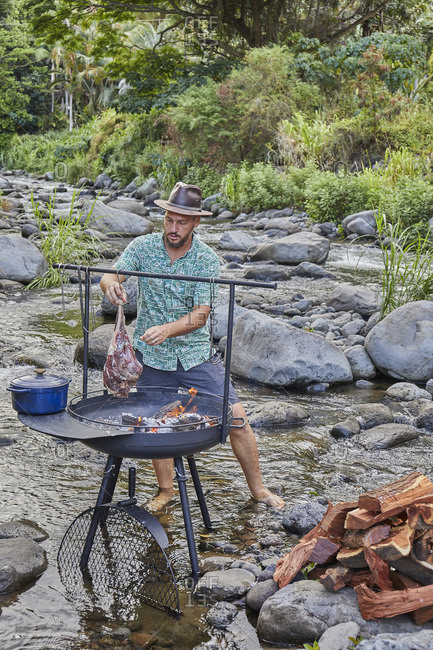 Chef Cooking over Open Fire at Campsite near Streambed