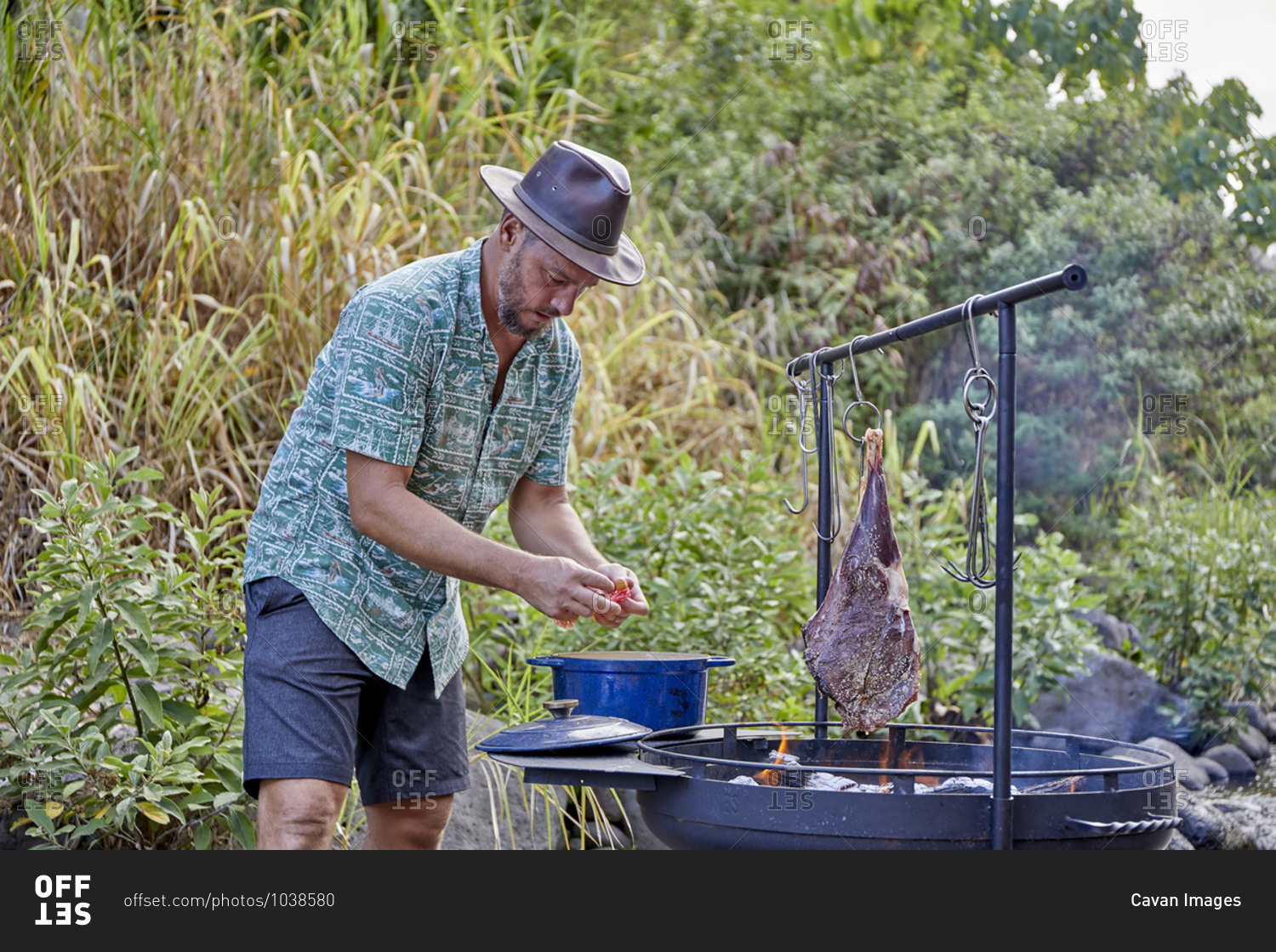 Chef Cooking over Open Flame at Campsite Along Streambed