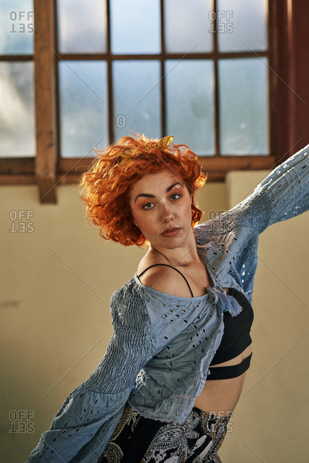 Young alternative redhead girl dancing in a blue blouse