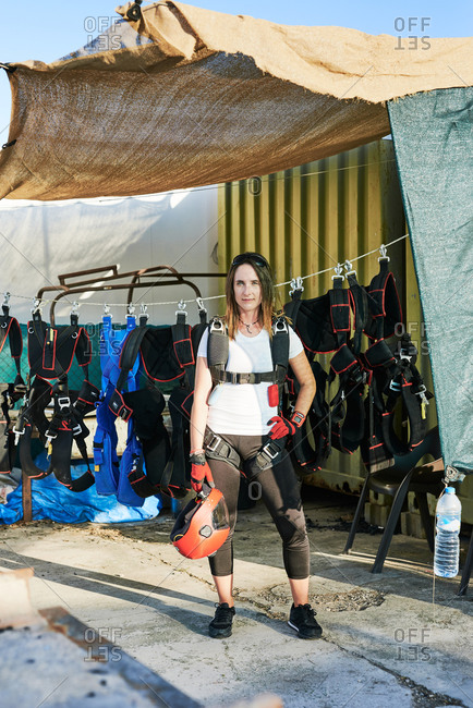 Young female skydiver with parachute backpack, gloves and helmet