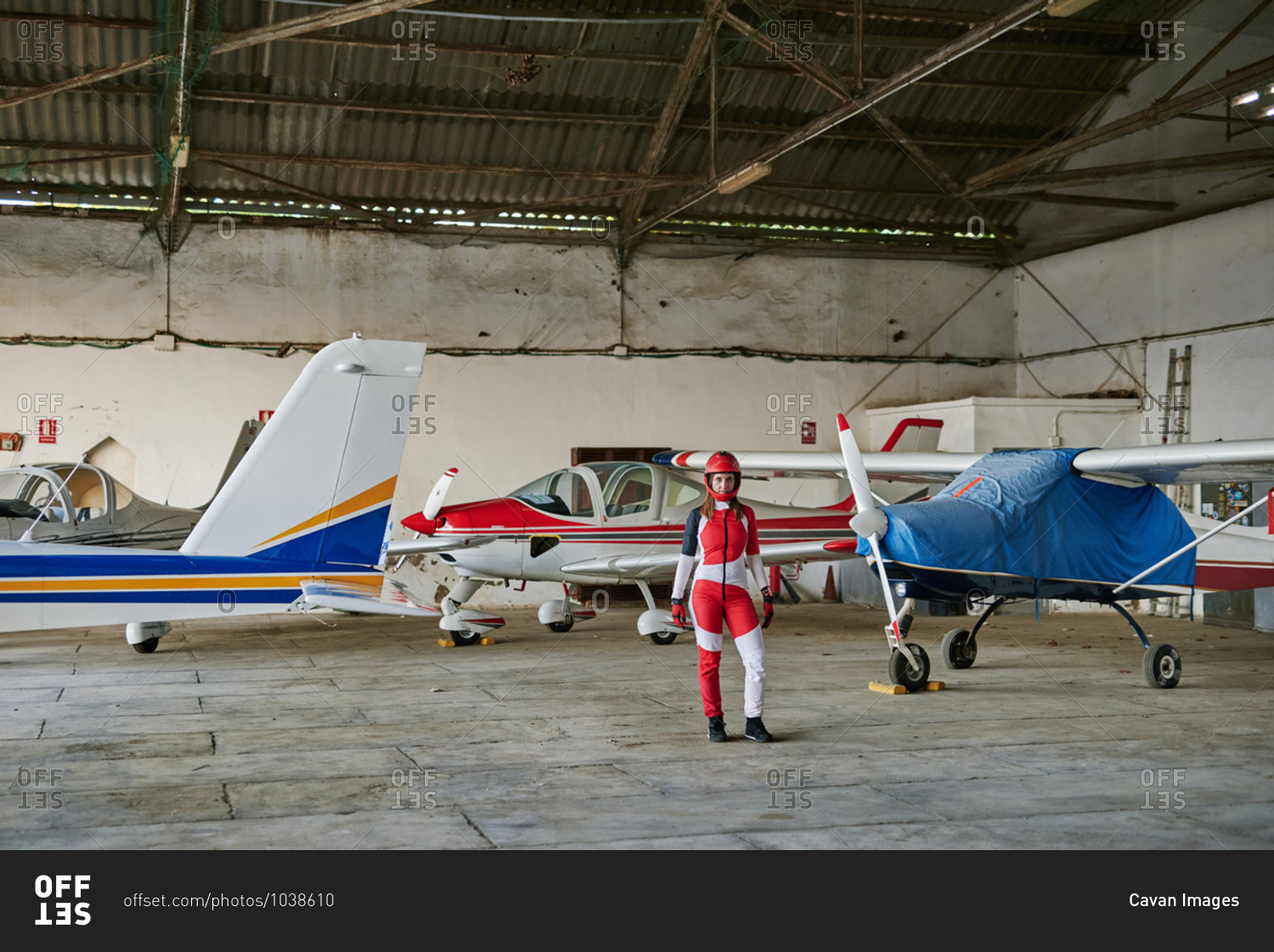 Young female skydiver in a plane hangar surrounded by planes