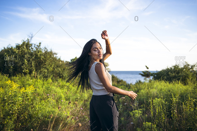 Black Multiracial Woman lifestyle portrait by the ocean at golden hour
