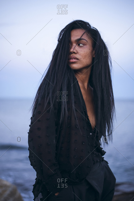 Black Multiracial Woman lifestyle portrait by the ocean in a swimsuit
