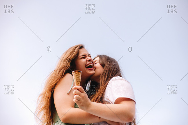 Happy lesbian couple romancing standing against blue sky in summer
