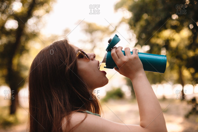 Teenage girl drinks water from bottle Stock Photo by