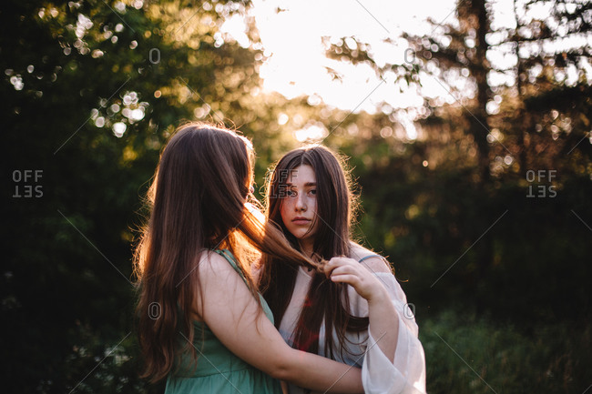 Young lesbian couple romancing while standing in forest during summer