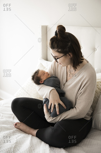 Hipster Millennial Mom Smiles Down at Swaddled Newborn Son