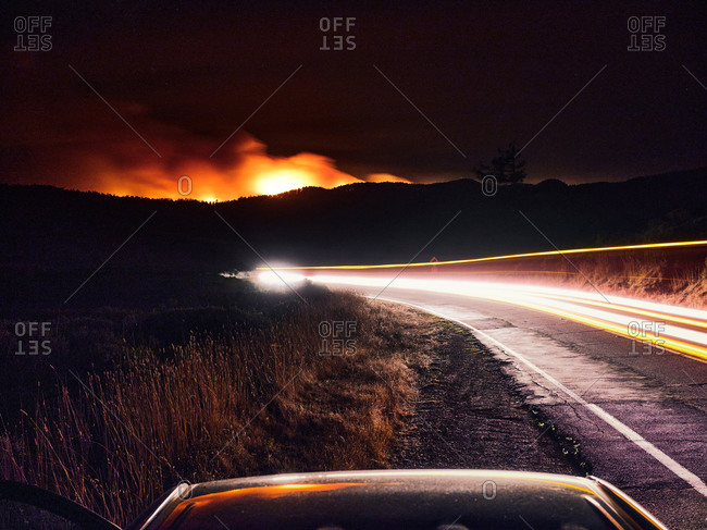 Blurred headlights on a dark road, Woodward Fire burns in Point Reyes.