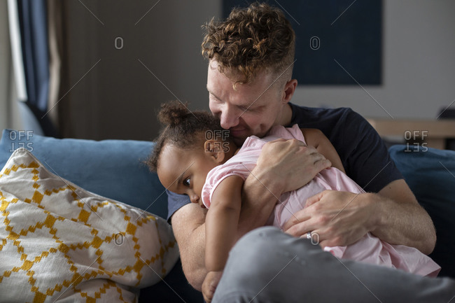 A father cuddles his sleepy daughter