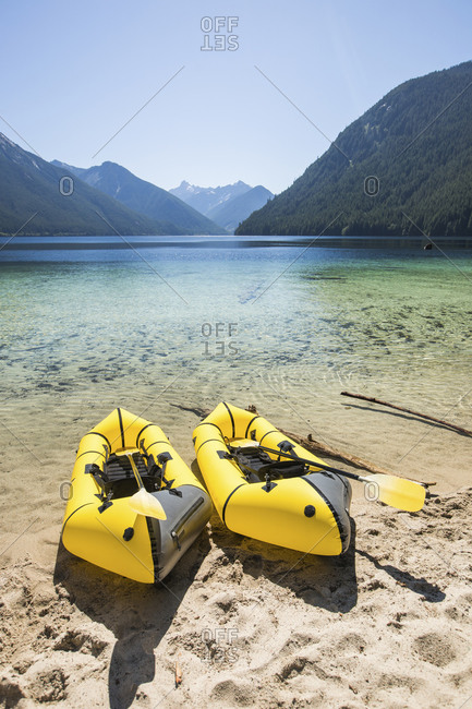 Two packrafts on the shore of a turquoise lake,