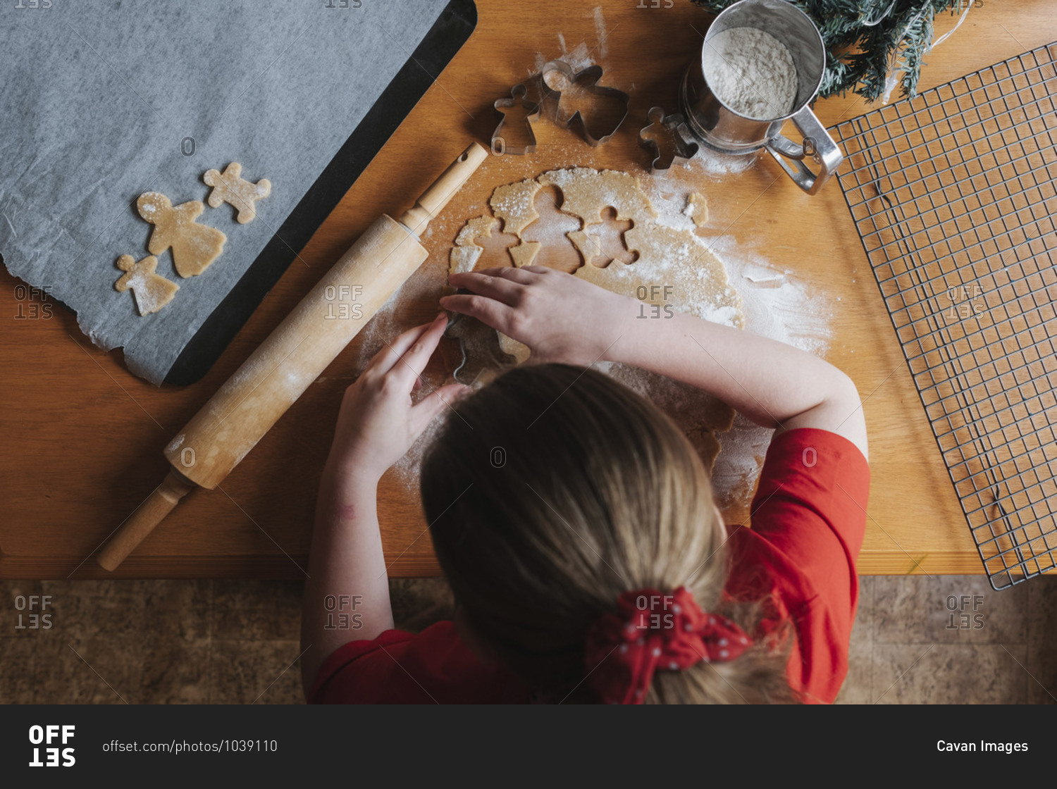 Young girl cutting out gingerbread dough on a wooden table