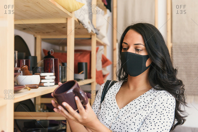 Woman wearing mask and browsing products in artisan home decor store