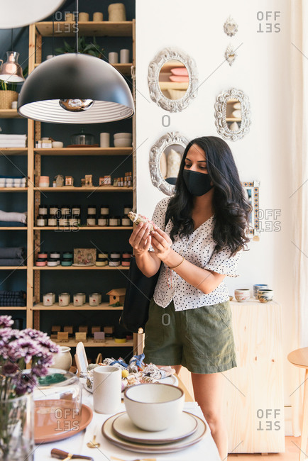Woman looking over home and beauty products in store with mask on