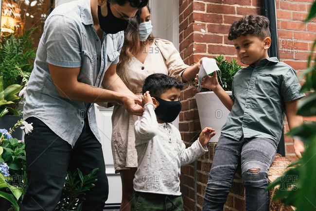 Parents helping young kids put on masks before going out of home