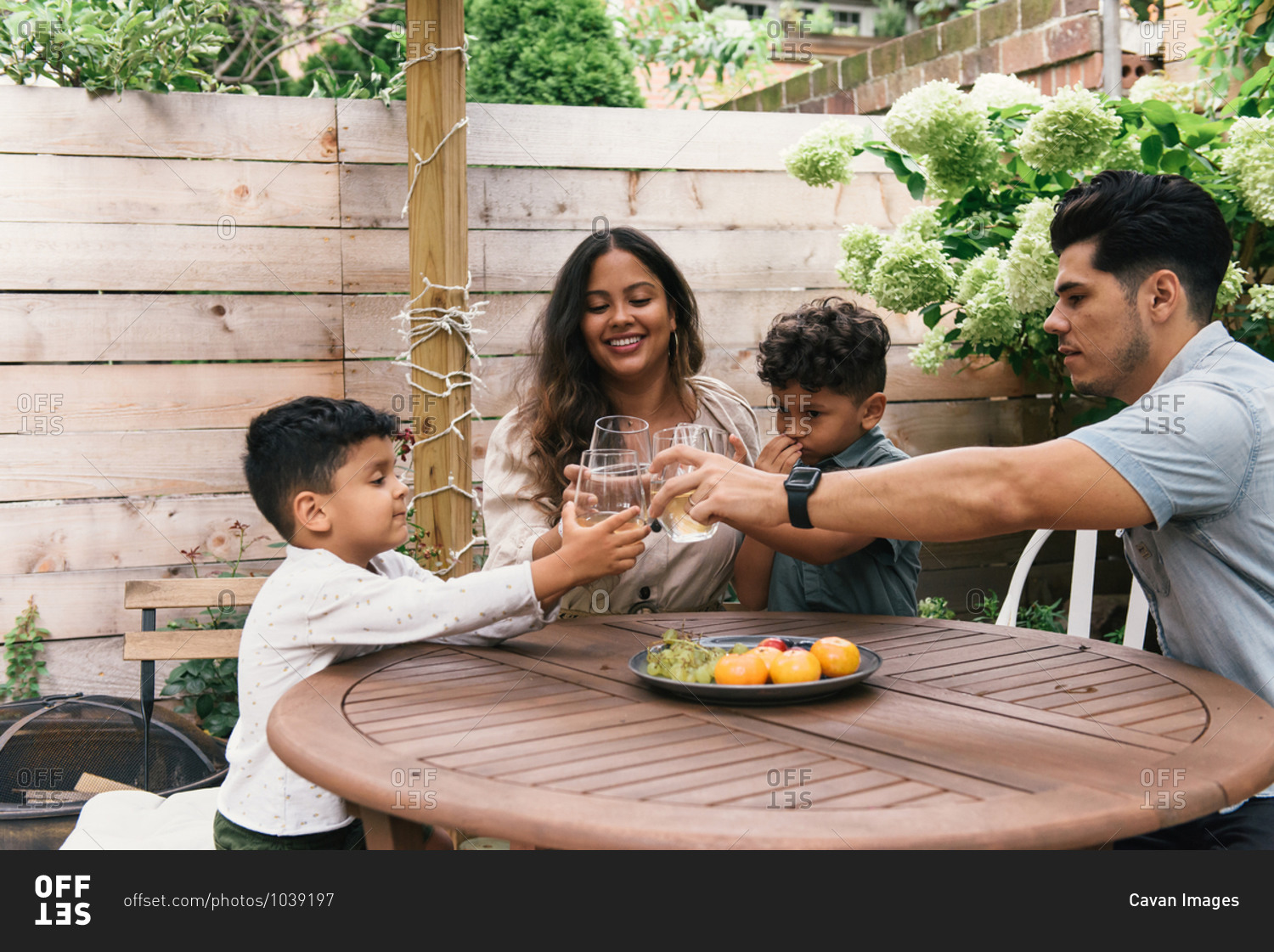 Young family in the backyard cheers with glasses during summer day