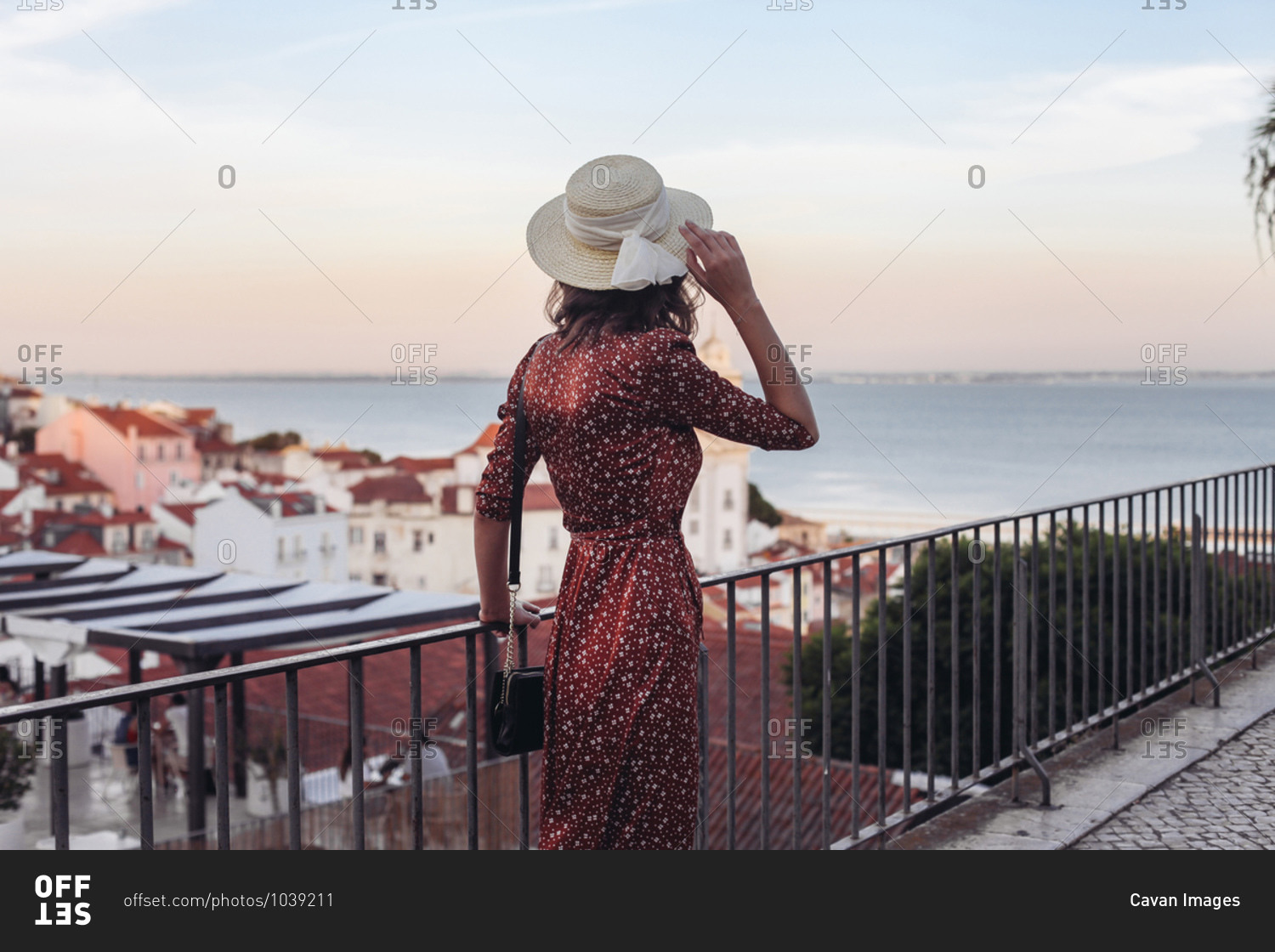 Woman in dress and a straw hat from the back, rooftop Lisbon view