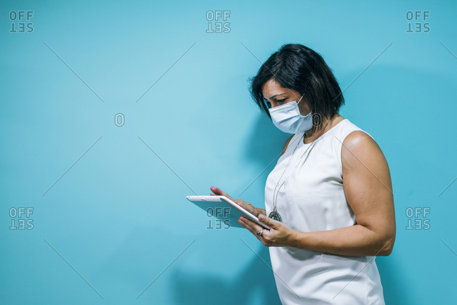 Portrait of a young business woman wearing a mask using a tablet
