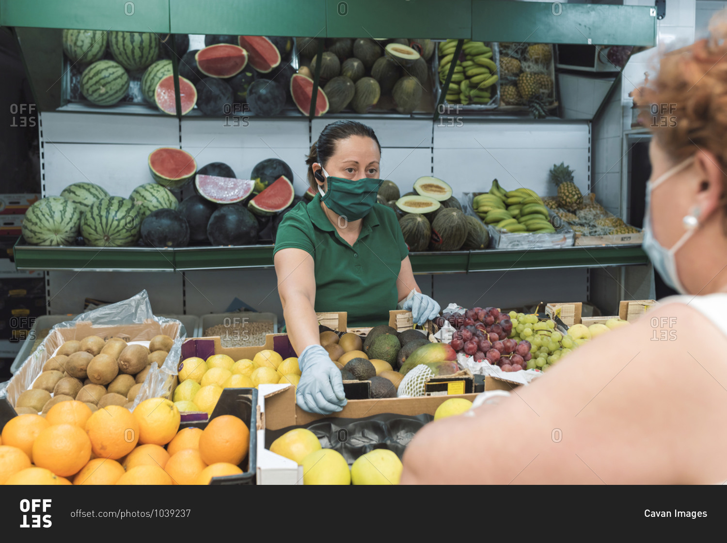 A shopkeeper with a mask attends to a customer in grocery store