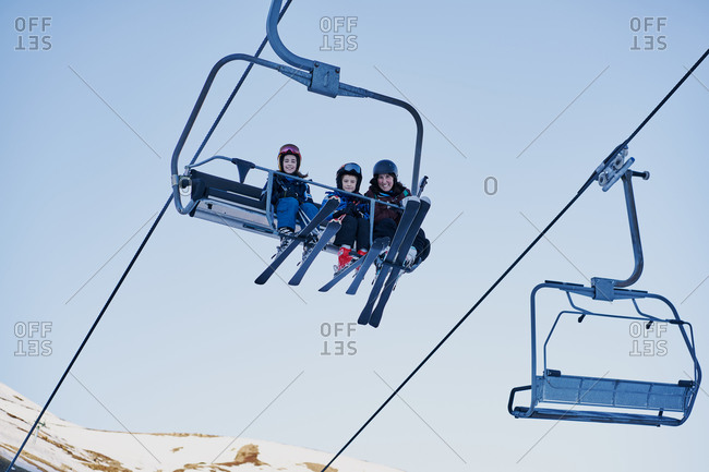 Skiers on a chairlift looking down with a blue background