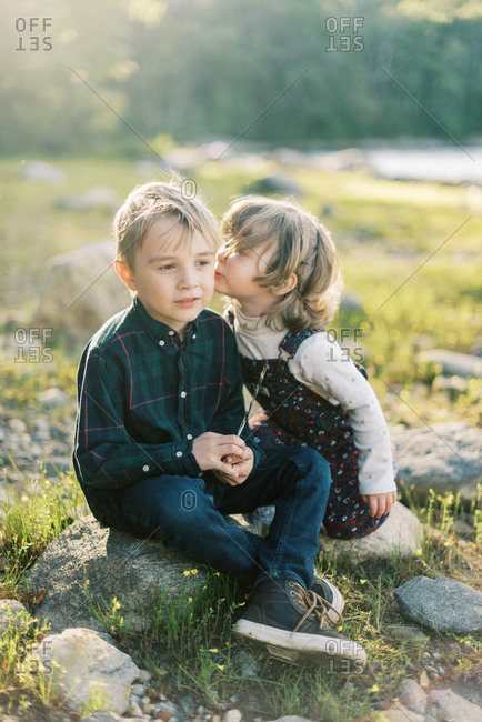 Two siblings whispering secrets to each other by the lake