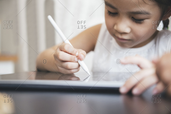 Little girl with tablet and stylus learning drawing online